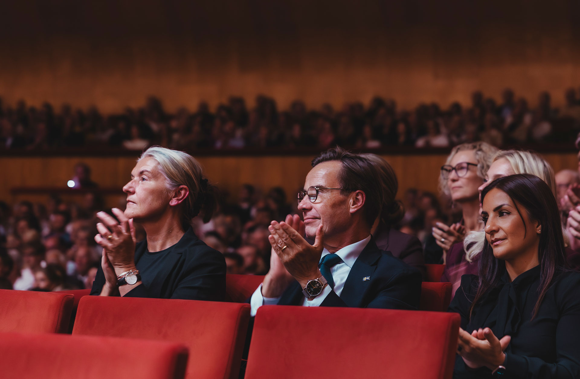 Tre personer som sitter i salongen applåderar.