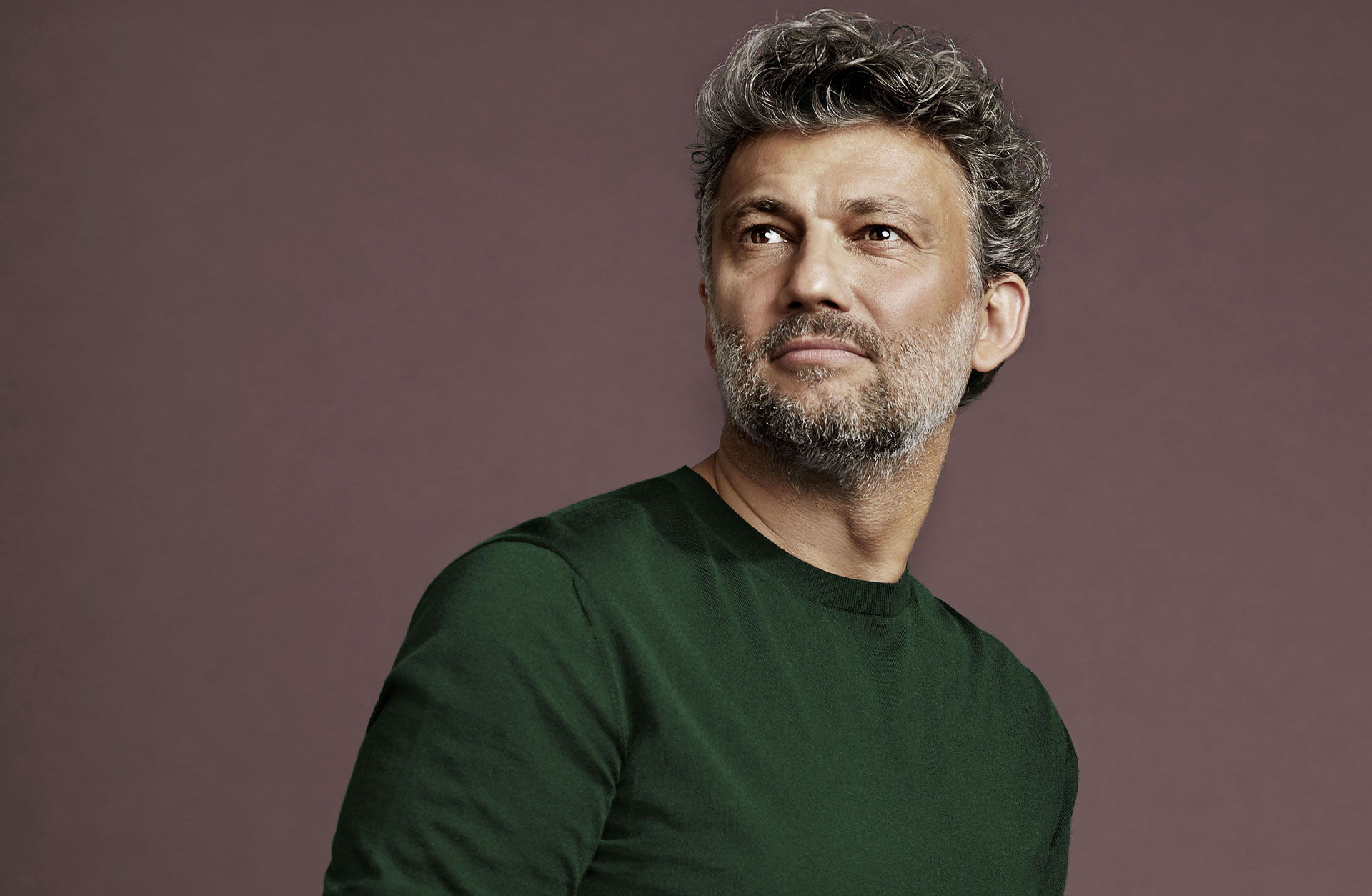 Porträtt av en gråsprängd man i grön tröja.