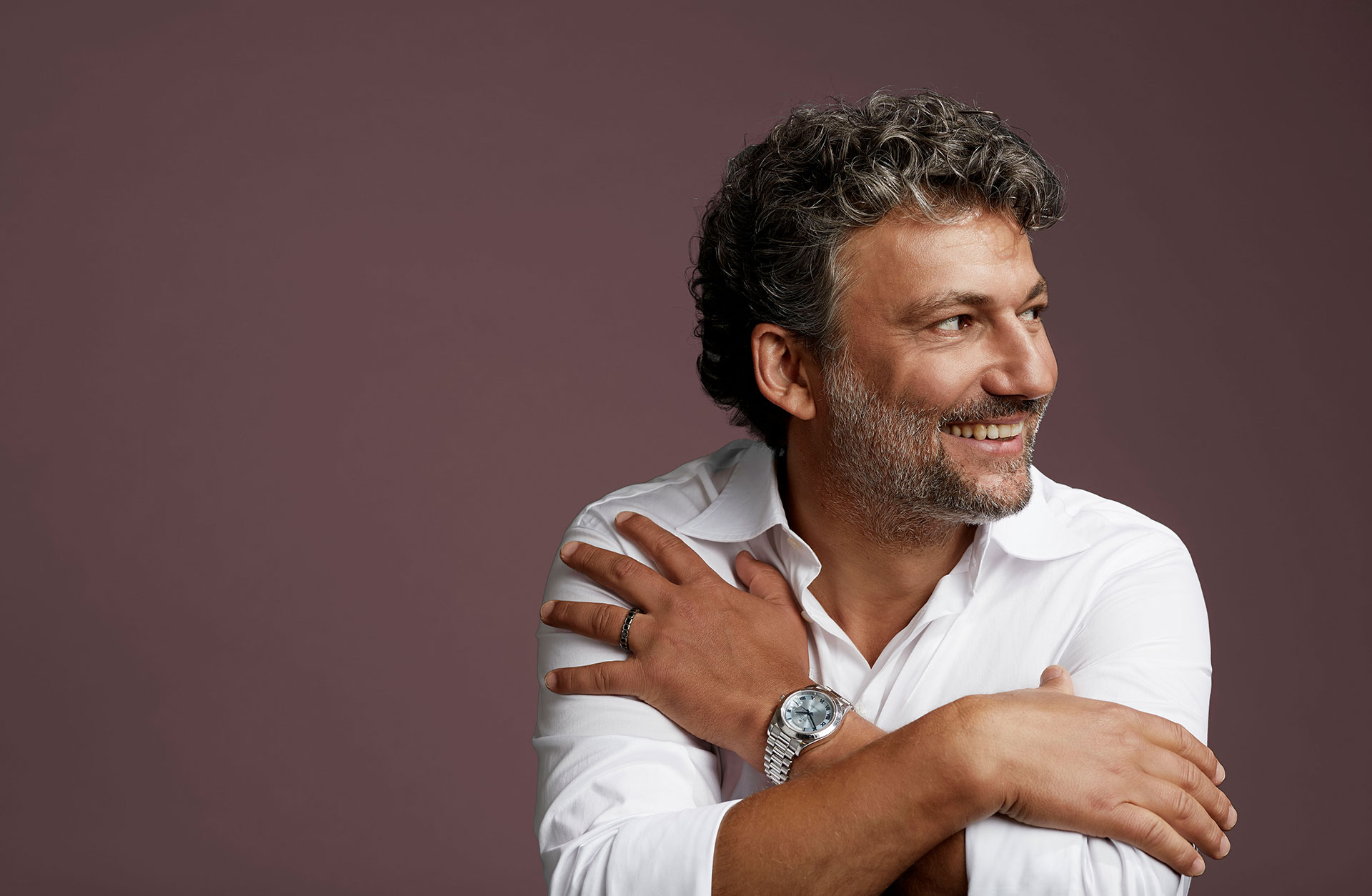 En man sitter med armarna löst i kors och tittar åt höger.