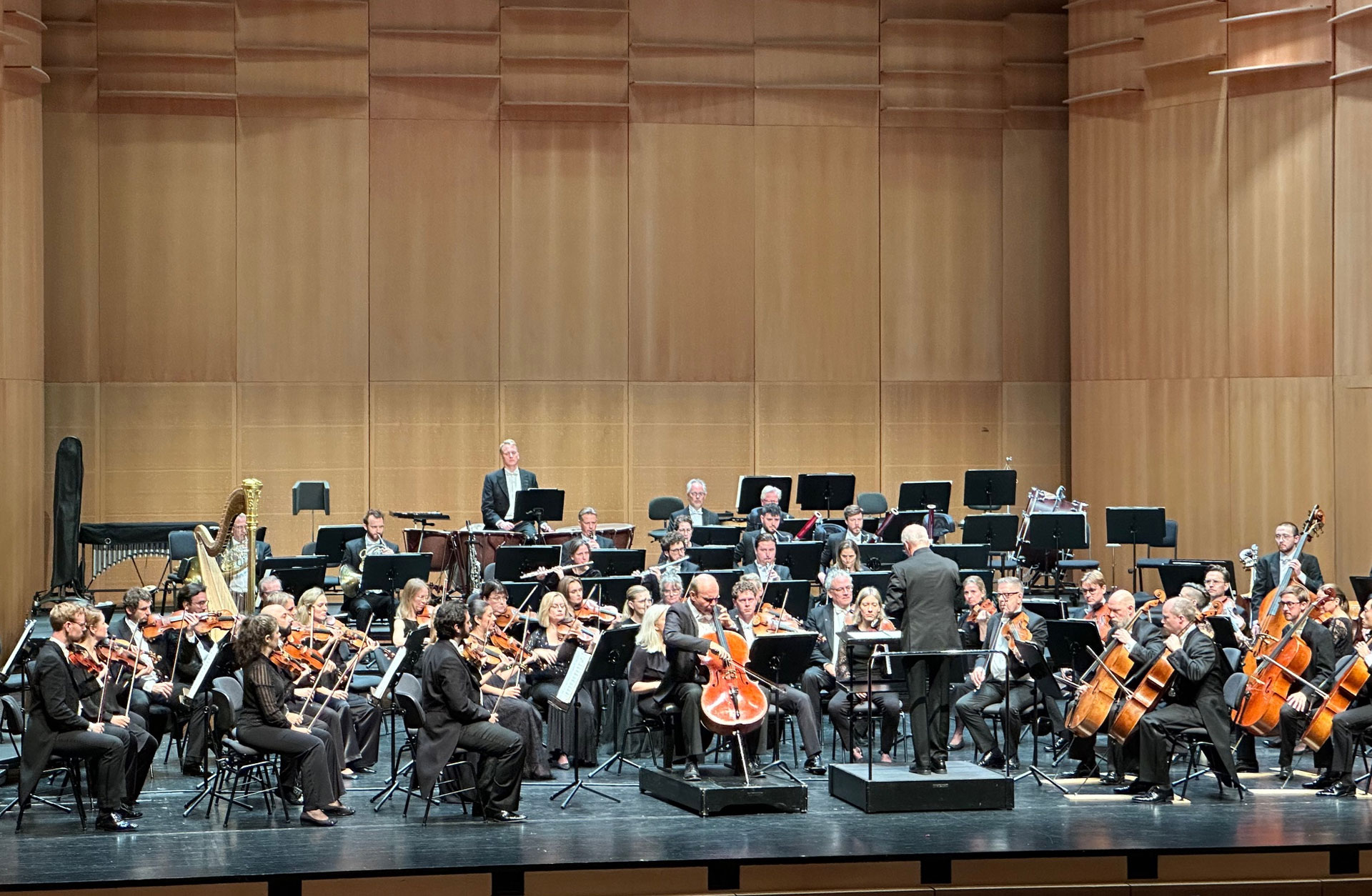 Orkestern på podiet tillsammans med cellist och dirigent.