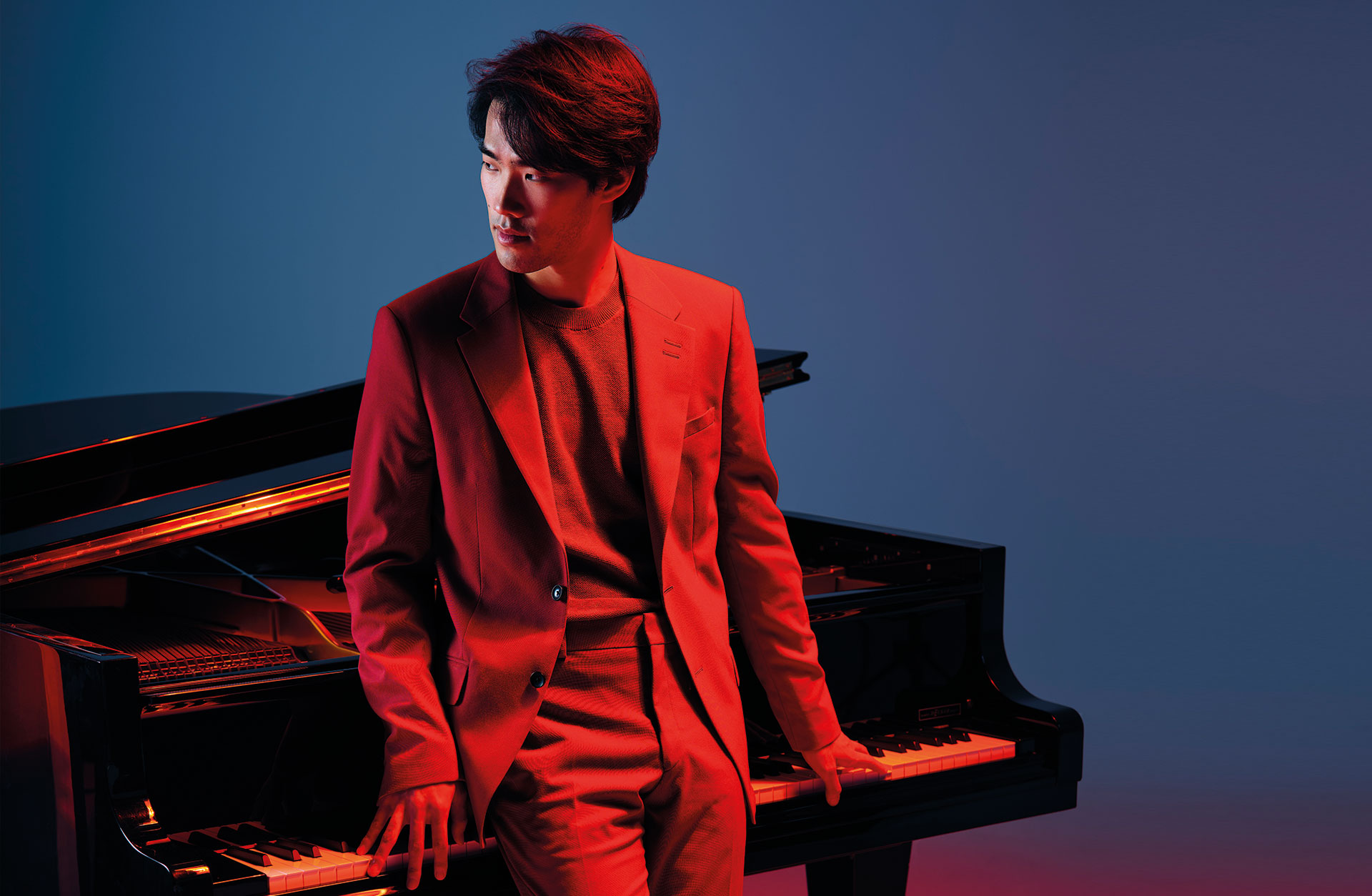 Man står lutad mot en flygel i rött ljus.