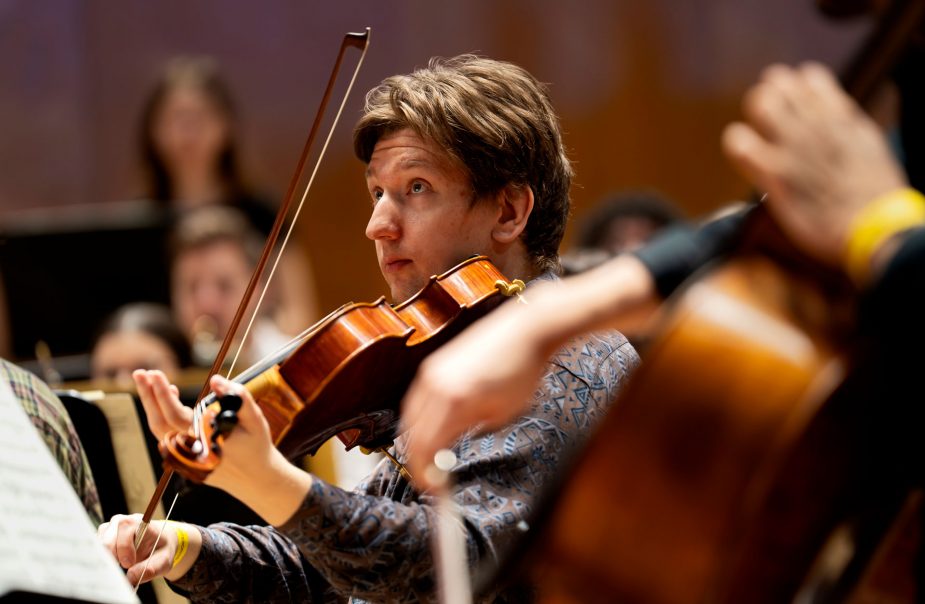 Närbild på en manlig violinist i en orkester.
