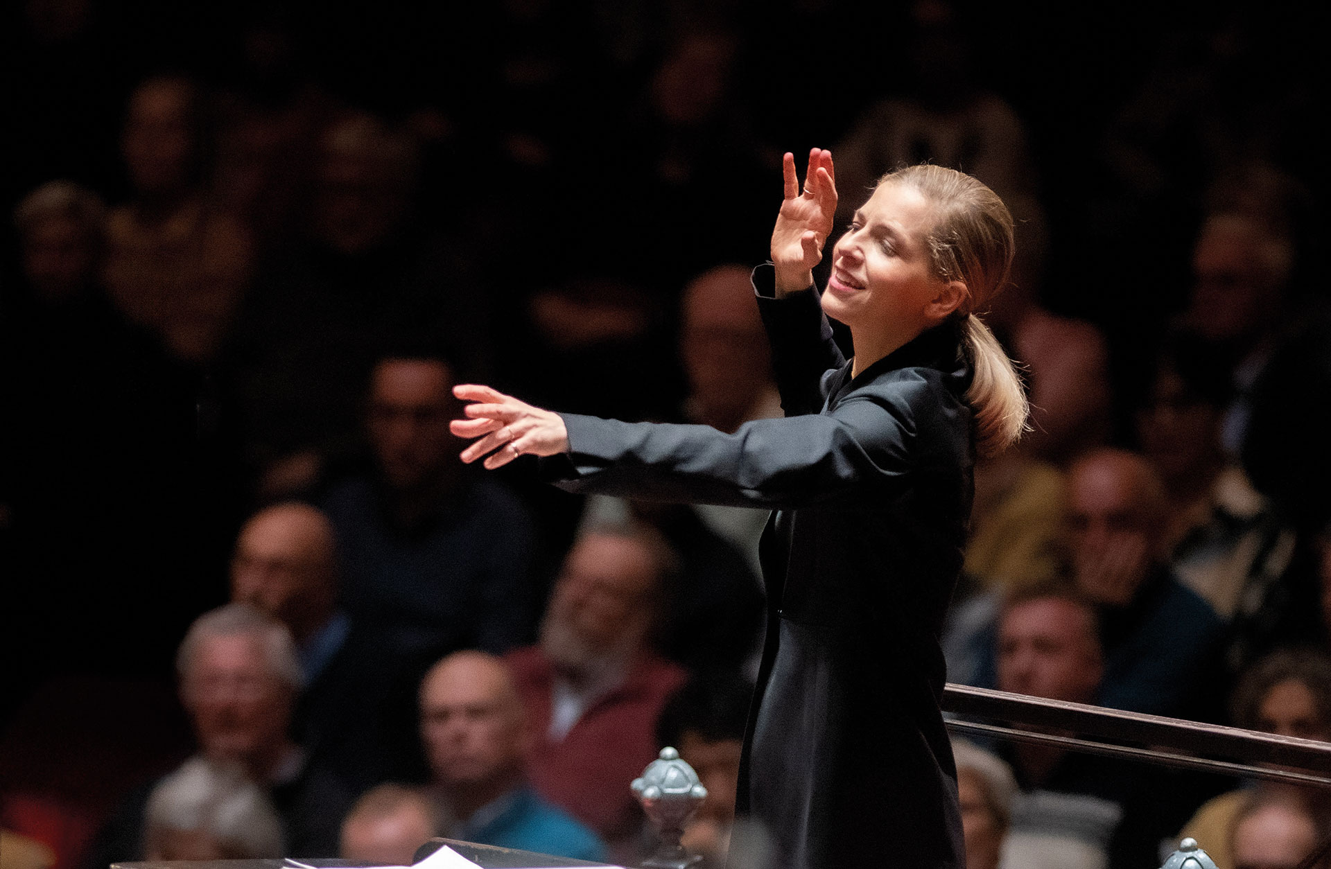 Kvinna dirigerar en orkester med kraftfulla gester.