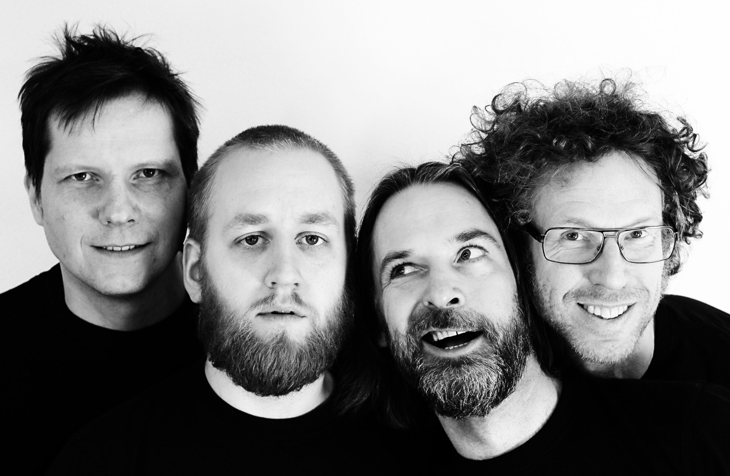 Fyra män mot vit bakgrund. Svartvit bild.