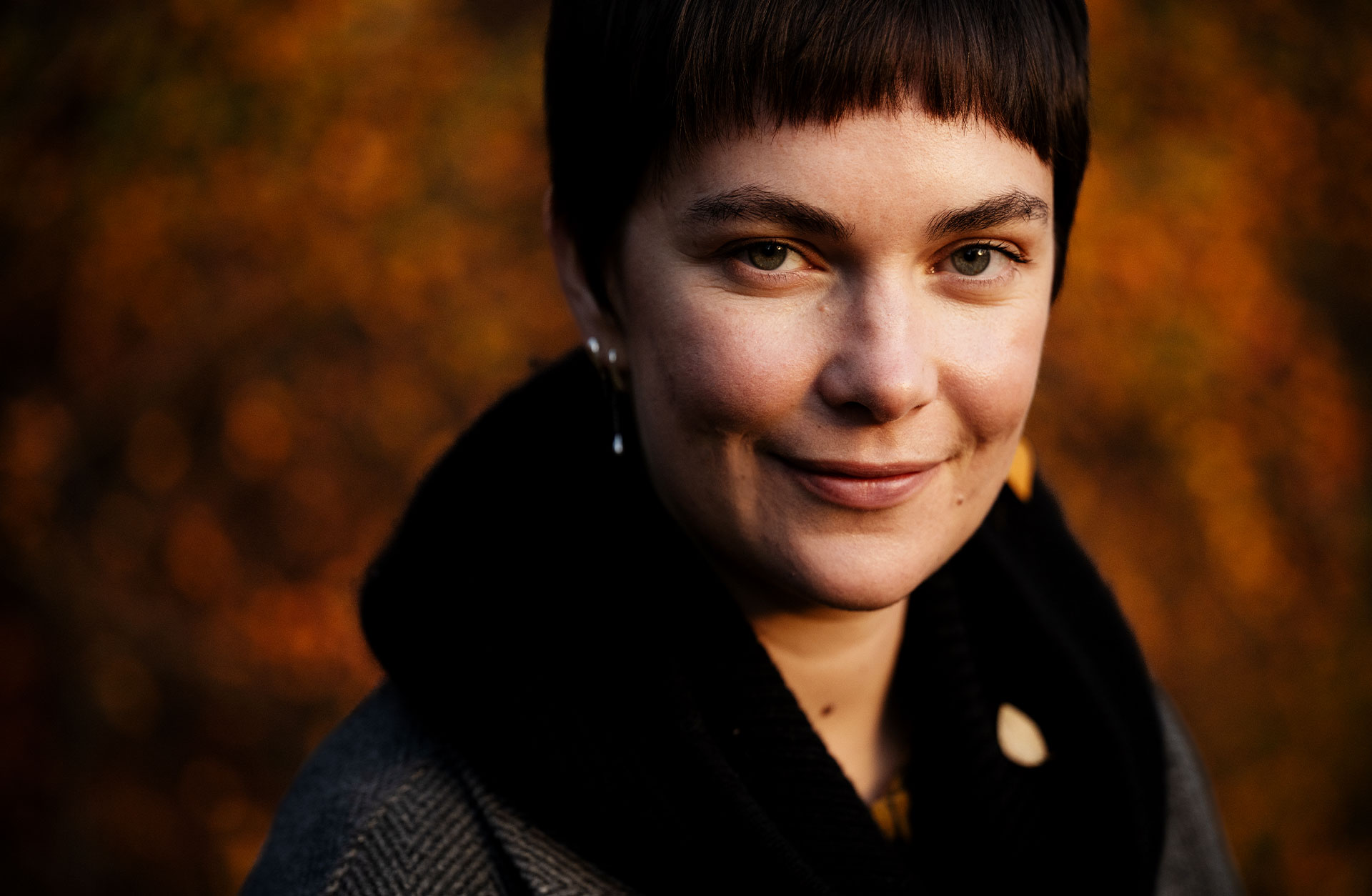 Ansiktsporträtt av en korthårig ung kvinna som ler och tittar in i kameran.