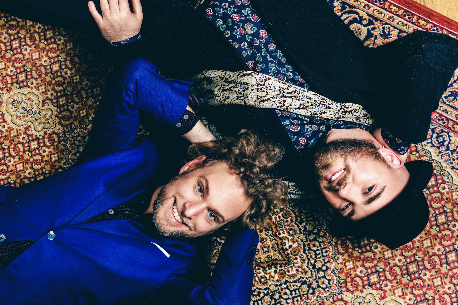 Två killar ligger på en flerfärgad matta