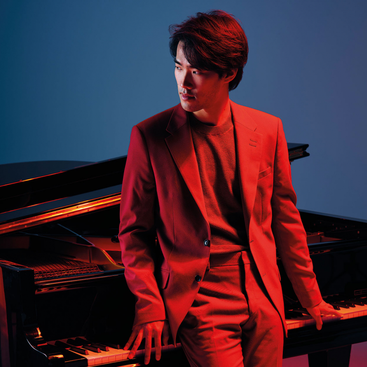 Man står lutad mot en flygel i rött ljus.