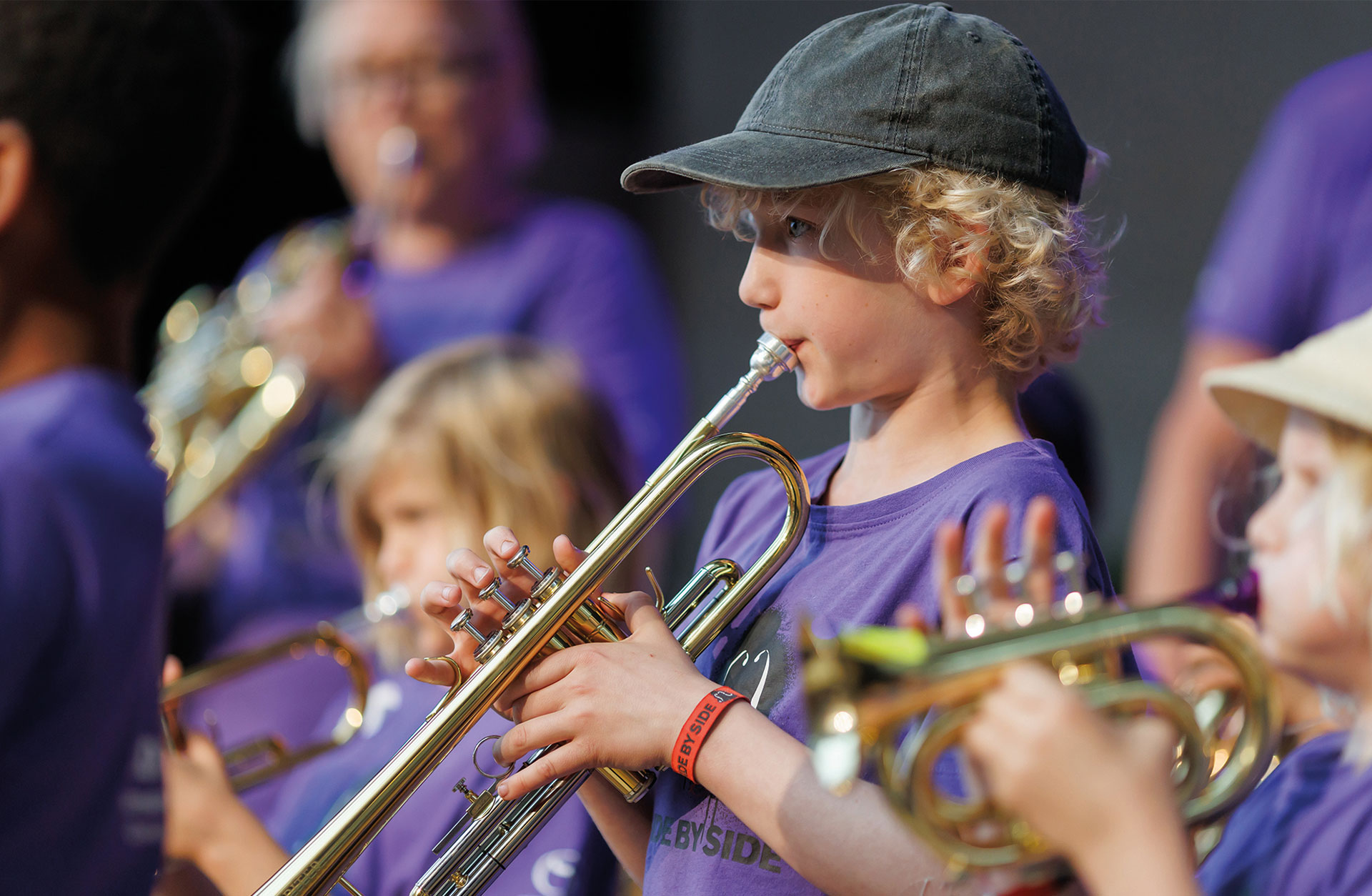Liten pojke med keps spelar trumpet.