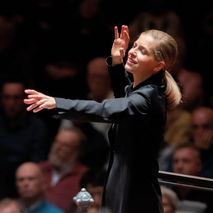 Kvinna dirigerar en orkester med kraftfulla gester.