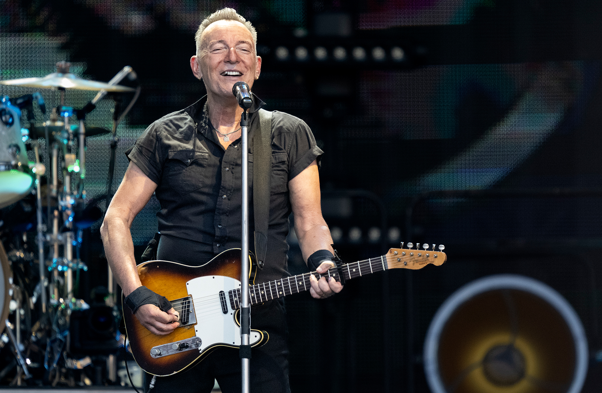 Närbild av Bruce Springsteen som spelar gitarr och sjunger in i en mikrofon.
