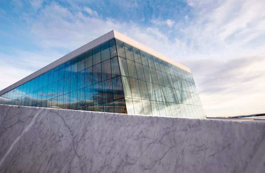 Glasparti på Oslo Operahus sticker upp mot en blå himmel.