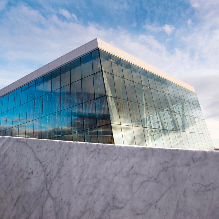 Glasparti på Oslo Operahus sticker upp mot en blå himmel.