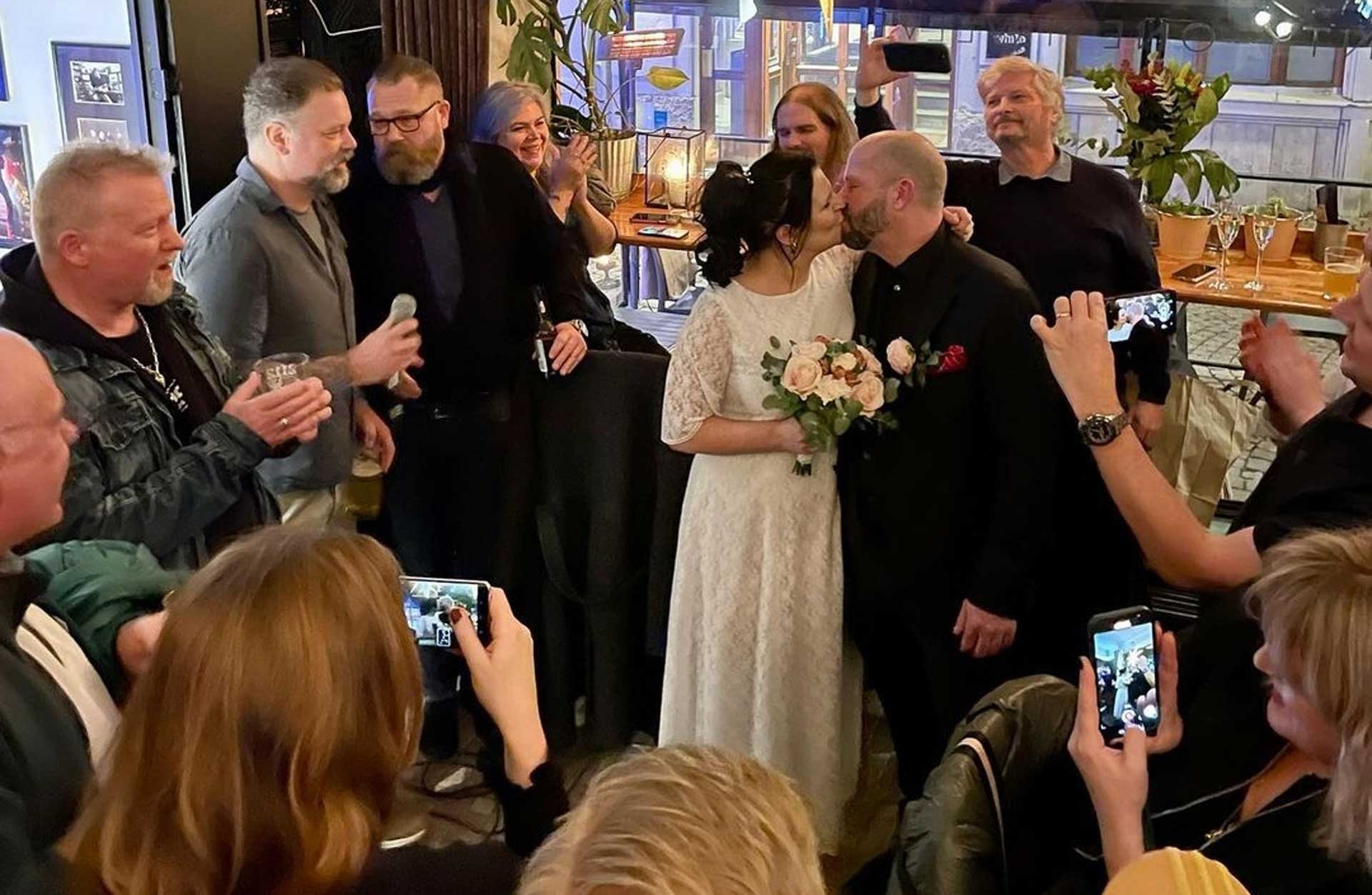 En folksamlig på en restaurang runt ett brudpar som kysser varandra.